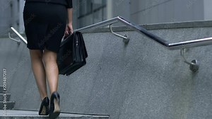 Young woman confidently walking up corporate ladder, diligence and hardwork