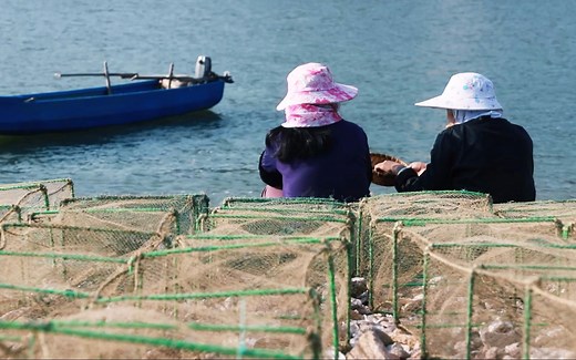 实拍海岛渔民出海捕捞的生活，渔家姑娘和妈妈在海边一起补笼，画面很温馨