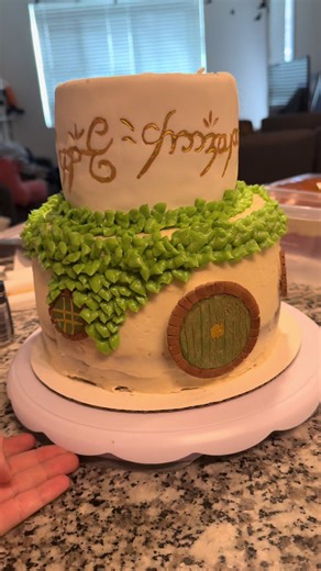 The early stages of my Lord of the Rings cake. It was definitely a “trust the process” type cake. The door and windows are made of fondant that I sculpted and painted with food coloring and cocoa powder. The One Ring is a fondant wrapped layer, then I hand wrote the text and used edible glitter to make it gold. #cake #fantasy #fantasycake #lordoftherings #lotr
