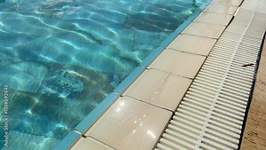 Swimming pool water pouring into the overflow grid. Grate for diversion of water in pool. Pool overflow system