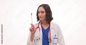Smiling woman dentist shows toothbrush reminding about oral cavity hygiene. Cheerful female demonstrates easy tool to prevent dental diseases