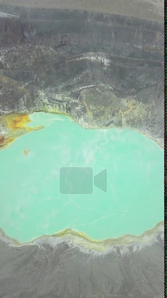 Aerial drone view of a turquoise crater lake inside a volcanic crater in Guatemala, surrounded by rugged volcanic rock formations and geothermal landscape. Vertical Stock Video Footage - Alamy