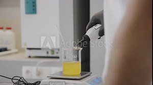 Scientist weighing samples on a digital scale in a laboratory with microscope and chemicals in background