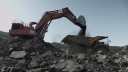 Excavator lifts bucket filled with coal and pours it into mining...