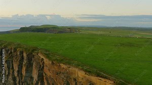 Pan shot transitions from fields to breathtaking views of cliffs and ocean