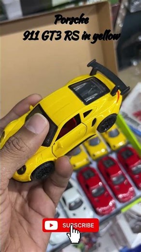 The toy car in the image is a die-cast scale model of a Porsche 911 GT3 RS in yellow