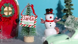 New Year or Christmas stop motion animation. A sign with the inscription santa, please wait here is moving on the christmas tree. Beautiful toy red door next to a snowman and fir trees