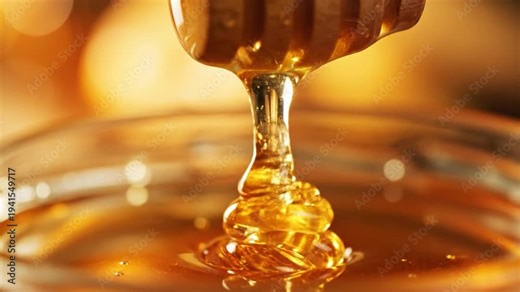 Golden honey dripping from a dipper into a jar
