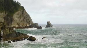Small sea stack protruding from turbulent Pacific Ocean off rocky Oregon Coast.