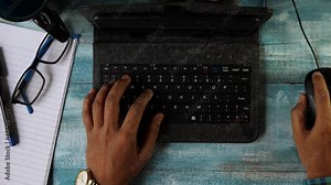 Top view of hands of an Indian man typing in keyboard of mini computer