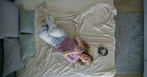 A woman laying on a bed with a controller