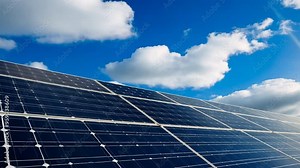 A solar panel is shown in the sky with a blue sky and clouds. The solar panel is a symbol of clean energy and a way to reduce our carbon footprint