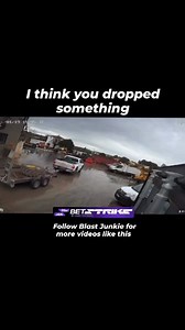 This intense CCTV footage captures a dramatic and unexpected explosion in a commercial yard. As a white pickup truck casually drives through the rain-soaked lot, a massive blast erupts just feet away, sending a thick cloud of smoke and a large piece of debris—appearing to be a heavy tire or container lid—soaring high into the air. ​Despite the shocking proximity of the blast and the debris crashing back down, the driver continues moving, and the person filming the monitor reacts with surprising 