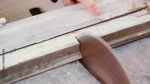 Old wooden window frames are sawn on a machine with a circular saw
