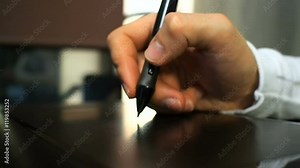 Tablet 21. Close up of the hand of a graphic designer clicking button on electronic stylus like right mouse button. Left view.