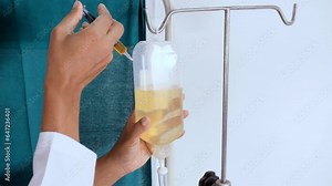 Closeup shot of a nurse injecting medicine from a syringe into a saline bottle - intravenous drip iv drip bottle. An infusion bottle with a medical solution - infusion therapy medical equipment ...
