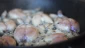 Traditional cooking of fried frog legs on pan.