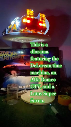 This is a diorama featuring the DeLorean time machine, an Alfa Romeo GTV, and a Lotus Super Seven.