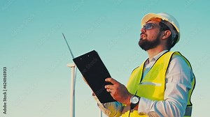 Wind turbines green energy. inspector holds a clipboard and checks the checklist for each turbine in the wind park