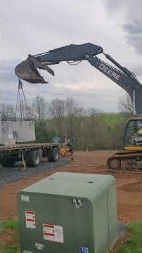 Trachoe off loading storm structure off of a flatbed tractor trailer.