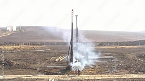 Excavation at a construction site, diesel pile driving machine with rumble and smoke drives piles deep into the ground to ensure the strength of the foundation of the future structure