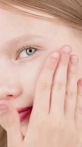VERTICAL VIDEO. Portrait of a beautiful cute young girl taking care of her face skin. Blonde Caucasian girl with blue eyes in studio. Advertising concept of skin care for teenagers. Acne treatment.