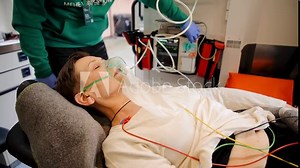 Female patient breathing through oxygen mask. Support in ambulance next to heart rate machine. Mature woman breathing with oxygen air supply