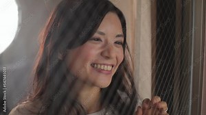 Japanese woman looks outside of the window. Emotion of happiness and joy. Slow-mo.