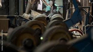 Automated pipe processing conveyor line at the production factory. Automated equipment processing the metal pipes on the industrial line. Automated factory machine deals with the pipe processing.