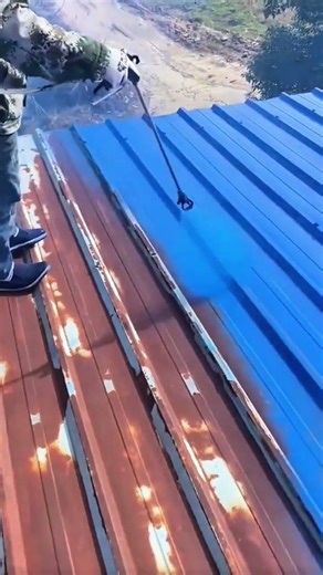 Painting rusty metal roof panels with bright blue spray paint very neatly and also very precisely