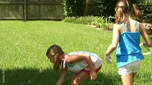 Two cute little girls playing with homemade wands and bubble solution in their backyard.