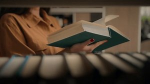 Close-up unrecognizable woman reading book in library female student teacher standing near bookshelf turning page textbook reads fiction preparing for university exam studying next to shelves books