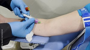 Capture of a woman having her blood drawn for testing. The camera slightly moves as the nurse changes the collection vial.