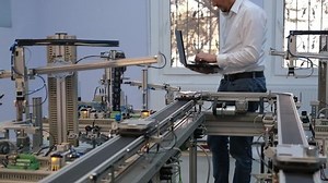Industry 4.0 concept; Engineer is working on laptop to program smart factory prototype's automation. automated car on production line, artificial intelligence in smart manufacturing.