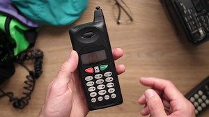 Using a retro cell phone from the 80s 90s. Top view from above over a retro 80s 90s desk.