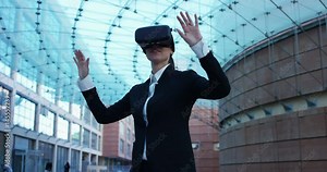 A beautiful career woman uses virtual reality, in the background the business centre. The business woman playing and having fun with augmented reality. Concept: insurance, business,immersive technolog