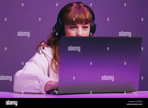 Female gamer looking focused at her laptop screen while playing an online video game in a studio. Woman using an interactive streaming service Stock Photo - Alamy