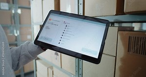 Postal Warehouse Worker Scans QR Code on Cardboard Box with Barcode Scanner, Monitors Package Information. Tablet Computer Screen Shows Delivery Tracking Software to Check Parcel Routing. Close Up.