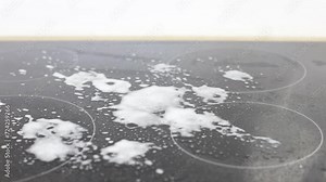 Cleaning induction electric stove at kitchen countertop. close up housewife's hands cleans kitchen induction hob with cleaning spray.