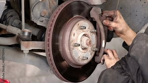 Disk brake pad and car disk brake system change service. Car disk brake pad replacement service by hand of mechanic man in car garage. Process of replacing brake pads with new. Dirty hands no glove