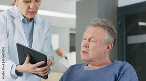 In the Hospital Female Doctor Shows Tablet Computer to Elderly Patient, Explaining his Condition. Modern Hospital with Best Possible Care. Shot on RED EPIC-W 8K Helium Cinema Camera.