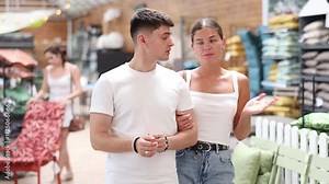 Married couple look for something in room garden furniture store, searching for perfect item to complete patio. Woman with husband buyers looks around in showroom. High quality 4k footage
