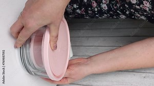 A woman examines glass food containers with plastic lids. Reviews the purchase. Containers of different sizes, stacked one on one. Vertical video