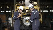 Technicians work at train engine repair shop. Machinery and...