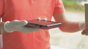 Close up a man hand using smartphone to scan QR code payment for online goods fee. Delivery courier woman wearing rubber gloves holding a parcel for sending to customer at home.