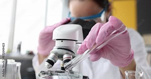 Scientist chemist pour pink liquid from test tube for examination under microscope. Development of toxic liquids concept