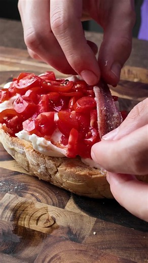 Bruschetta con Pomodori marinati, burrata, acciuga e basilico.