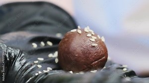 Adorning handmade chocolate delicacies with sesame seeds. Female confectioner shares vision for crafting sweets displaying culinary viewpoint