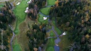 Aerial view of Golf course near the forest. Establishing shot, drone flying over country golf club. Autumn, cloudy. Beautiful prestigious green golf course with river and trees. Drone areal view shot