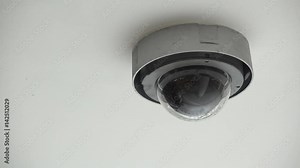 Dome camera located inside office building watching employees as they work.